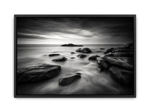 Black and white ocean wall art with dramatic coastal rocks, misty waves, and moody storm clouds in contemporary monochrome seascape style