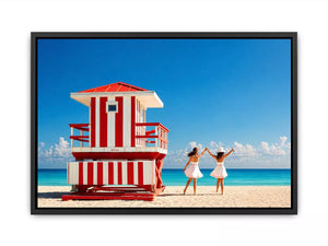 Minimal coastal beach scene with red lifeguard hut blue ocean and two women walking aesthetic Canvas Print