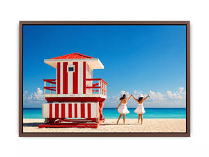 Minimal coastal beach scene with red lifeguard hut blue ocean and two women walking aesthetic Canvas Print