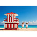 Minimal coastal beach scene with red lifeguard hut blue ocean and two women walking aesthetic Canvas Print