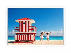 Minimal coastal beach scene with red lifeguard hut blue ocean and two women walking aesthetic Canvas Print