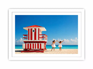 Minimal coastal beach scene with red lifeguard hut blue ocean and two women walking aesthetic Canvas Print
