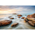 Serene coastal landscape wall art featuring smooth ocean waves, natural shoreline rocks, pastel sunrise sky, and luxury long exposure beach photography for modern coastal interiors