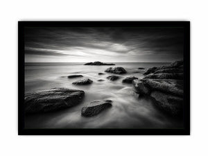 Black and white ocean wall art with dramatic coastal rocks, misty waves, and moody storm clouds in contemporary monochrome seascape style