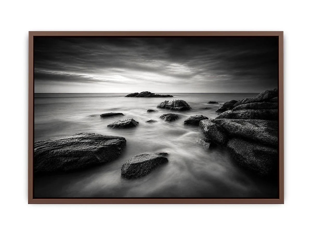 Black and white ocean wall art with dramatic coastal rocks, misty waves, and moody storm clouds in contemporary monochrome seascape style